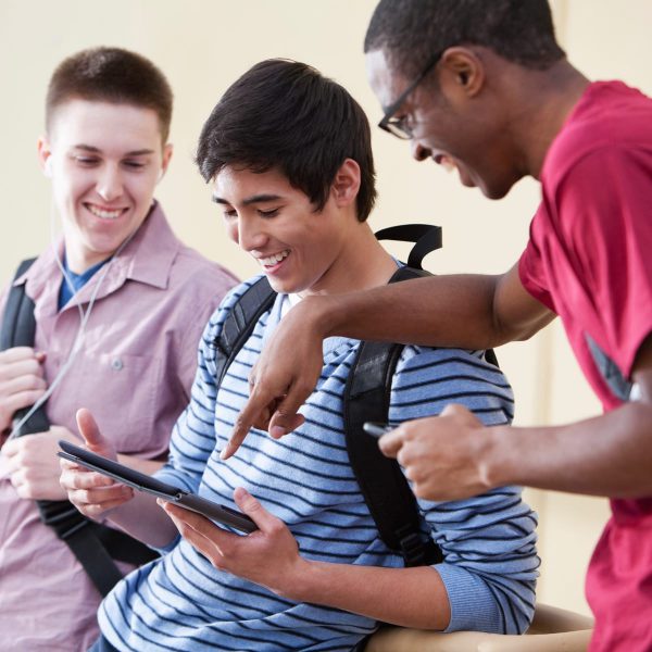 A group of teenage boys gathered around d a tablet